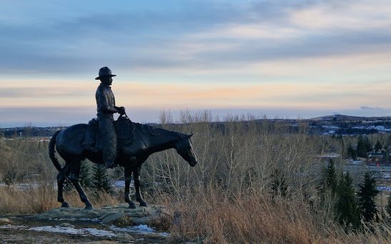 The Men of Vision statue overlooking Cochrane at dusk